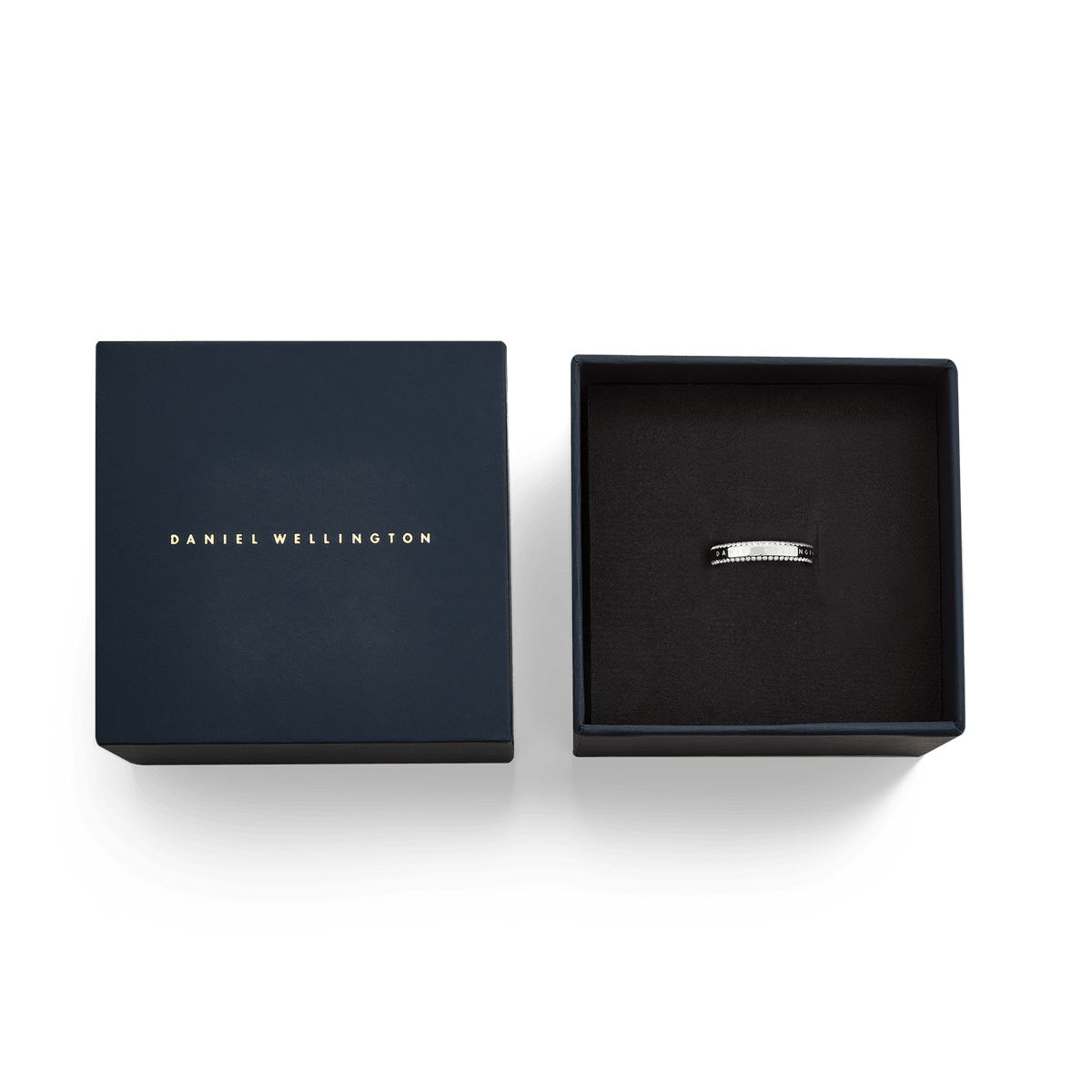 ダニエルウェリントン Classic Aura Duo Ring Silverを、ネイビーの専用ギフトボックスに収めた状態を真上から撮影した画像です。ゴールドのロゴが入った蓋が左側に置かれ、右側のボックス内にはシルバーリングが丁寧にセットされています。