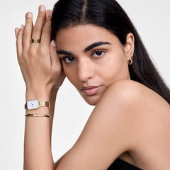 Quadro Roman Numerals 5-Link Goldを身に着けた女性のスタイリングイメージです。ゴールドのバングルやリング、フープピアスと合わせ、ジュエリー感覚でコーディネートしています。