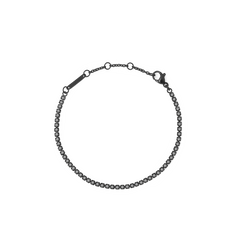 Daniel WellingtonのBlack Crystal Tennis Bracelet全体の様子です。ブラックPVD加工のスチールチェーンに、ダーククリスタルが一粒ずつセットされています。ロブスタークラスプとサイズ調整リングも確認できます。