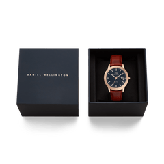 ダニエルウェリントンのアイコニックな「Iconic St Mawes Automatic Rose Gold」を、ネイビーカラーのギフトボックスに収めた贈り物に最適なセットです。ブラックの文字盤とブラウンのレザーストラップが美しく調和し、ブランドロゴ入りの蓋とともに上品な仕上がりとなっています。