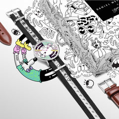 Steven Harrington x Daniel Wellingtonの限定コラボセットを、コラボレーションアートが描かれた専用パッケージとともに俯瞰で撮影した画像です。マルチカラーのプリントダイヤルとアイモチーフのNATOストラップを装着した腕時計の周囲には、付け替え用のSt Mawesレザーストラップやポップなキャラクターイラストが配置されています。