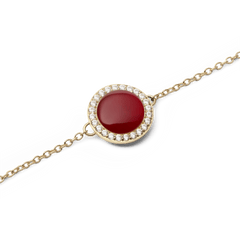 Audrey Bracelet Red Agathe Goldのチャーム部分をクローズアップした画像です。深みのあるワインレッドのドーム型赤メノウを、きらめくホワイトキュービックジルコニアが一周して囲み、繊細なゴールドチェーンと繋がっています。
