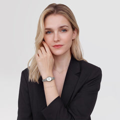ブラックジャケットを着た女性がOphelia Mini Mesh White Silverを手首に着用した様子です。小ぶりな楕円形ケースとシルバーメッシュのストラップが、繊細なブレスレットやネックレスとも調和し、上品なスタイリングを演出します。