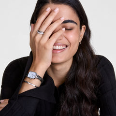 クラシックなLumine Bracelet Sをシルバーカラーのレクタンギュラー腕時計と重ね付けした女性の着用イメージです。黒いトップスに映えるシルバーアクセサリーのコーディネートで、クリスタルがさりげなく輝きを放っています。
