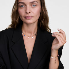 ブラックのジャケットを着用した女性が、Elementalコレクションのゴールドチャームチェーンネックレスとブレスレットを身につけたスタイリング例です。ブルージャスパーやピンク、ホワイトなど、さまざまな天然石のチャームを組み合わせています。