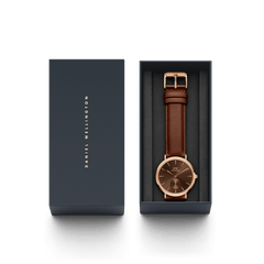 ダニエルウェリントンのギフトボックスに収められたClassic Multi-Eye St Mawes Amber Rose Gold。ネイビーのボックスにはブランドロゴが箔押しされた蓋があしらわれ、ダークブラウンのレザーストラップとアンバーカラーのダイヤルが美しく映える本体が並んでいます。パッケージ全体を上から見た画像です。