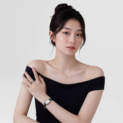 黒のオフショルダートップスを着用した女性が、グリーンのレザーストラップとシルバーケースの腕時計に、パール一粒のシルバーネックレスとリングを合わせたDaniel Wellingtonのスタイリング例です。