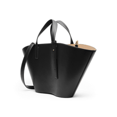 River Bag Blackを斜め後方から捉えた画像です。ウィングシルエットの左右非対称な広がりや、ブラックレザーの端正な表面が際立ちます。ショートハンドルとショルダーストラップの取り付け部分、開口部から覗くベージュの内装も確認できます。