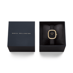 ダニエルウェリントンのギフトボックスに収められたMargot Reading Onyx Ceramic Gold。ブラックのクロコダイルレザーストラップとゴールドケースの腕時計が、クッション材の上に丁寧にセットされています。贈り物にも最適なパッケージです。