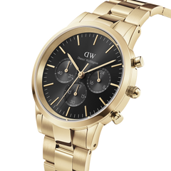 Iconic Chronograph Link Onyx Gを斜めからとらえたクローズアップ画像です。ゴールドケースの右側に配置されたクロノグラフプッシャーとリューズのディテール、ブラック文字盤に映えるゴールドのバーインデックス、そしてサテン仕上げとポリッシュ仕上げが織りなすリンクブレスレットの質感がご覧いただけます。