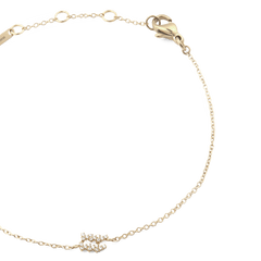 蟹座モデルのCrystal Zodiac Chain Bracelet Goldを半円状に配置したクローズアップ画像です。繊細なゴールドチェーンの下部には、クリスタルの蟹座シンボルが輝き、左上にはブランド刻印プレートとアジャスターリング、右上にはロブスタークラスプが確認できます。