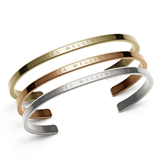 Daniel WellingtonのClassic Bracelet 3本セット（ゴールド、ローズゴールド、シルバー）。ブランドロゴが刻印されたオープンカフデザインで、ポリッシュ仕上げの外側とサテン仕上げの内側のコントラストが美しいアクセサリーです。