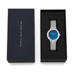Daniel Wellingtonのネイビー色のブランドボックスに収められたCrystalline Bezel Sterling Blueのギフトセットです。ブラックのクッショニング上に、シルバーメッシュストラップとブルーマザーオブパールダイヤルの腕時計が丁寧にセットされており、贈り物にぴったりの上品な仕上がりとなっています。