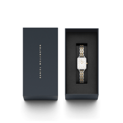 ダニエルウェリントン Quadro Lumine Bezel 5-Link Two-Tone MOPが、ネイビーの専用ギフトボックスに収められた状態です。箱の蓋にはゴールドのブランドロゴが刻印されており、贈り物にぴったりの上品なパッケージとなっています。