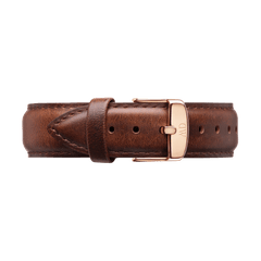 Daniel Wellington St Mawesのストラップをクローズアップでご紹介します。ブラウンレザーの自然な風合いと、尾錠側のベルト穴が並ぶ仕上がりがお分かりいただけます。ローズゴールドのピンバックルにはロゴが刻印されており、革のループにストラップの先端が通された状態です。