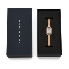 Daniel WellingtonのQuadro Mini Melrose Sunray Rose Gold Liningは、ネイビーのギフトボックスに収められています。ブラックのクッションの上にローズゴールドのメッシュストラップとスクエアケースが映え、贈り物にぴったりの上品なパッケージです。
