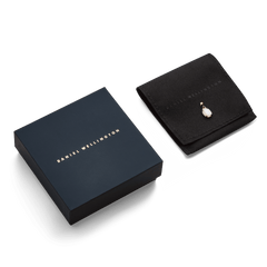 ダニエルウェリントンのネイビーのギフトボックスと、ブランドロゴ入りのブラックスエード調ポーチに収められたMother of Pearl Oval Gold Charmのパッケージです。贈り物にぴったりの上品な仕上がりとなっています。