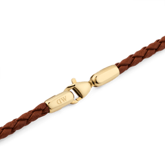 Braided Leather Bracelet St Mawes 2.8 Goldのゴールドロブスタークラスプ部分をクローズアップした画像です。ブランドロゴが刻印された光沢のあるPVDゴールドメッキの金具と、ライトブラウンの編み込みレザーとの接続部分がご覧いただけます。