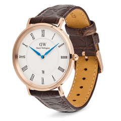 ダニエルウェリントン Classic Roman Numerals Date Dark Brown Croc Bellyを斜め上から撮影した画像です。ローズゴールドのケースやリューズ、ダークブラウンのレザーストラップの裏地やステッチの細部まで確認できます。ホワイト文字盤にブルーの針が鮮やかに映えるデザインです。