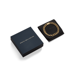 ダニエルウェリントンのChunky Chain Bracelet Goldを、ネイビーのブランドギフトボックスとブラックのジュエリーポーチとともにパッケージした画像です。贈り物にもぴったりの上品な仕様となっています。