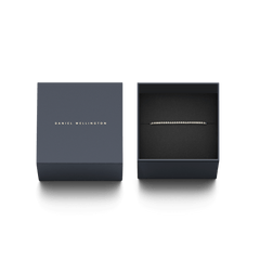 ダニエルウェリントンのブランドロゴ入りギフトボックスに収められた、Classic Tennis Braceletのゴールドモデルです。ダークグレーの専用ボックス内で、黒いクッションカバーの上にキュービックジルコニアが輝くブレスレットが丁寧にセットされており、贈り物にぴったりの上品な仕上がりとなっています。