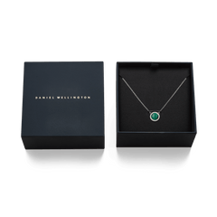 Audrey Necklace Malachite Silverがダークネイビーのブランドギフトボックスに収められた様子です。蓋にはDaniel Wellingtonのロゴが金色で刻印され、ボックス内のブラッククッションの上にマラカイトのペンダントとシルバーチェーンが丁寧にセットされています。