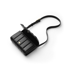 Daniel WellingtonのSadie Bag Blackを上から撮影した俯瞰画像です。フラップを開いた状態で、ゴールドのマグネットボタンと縦パフキルティングの立体的なラインが際立ちます。長さ調節可能なブラックレザーのストラップはS字に広がり、ゴールドのバックル金具がアクセントになっています。