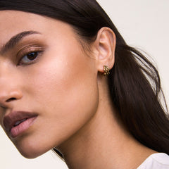 ダニエルウェリントンの5-Link Earrings Goldを着用したモデルのクローズアップ写真。5連リンクのコンパクトなゴールドフープピアスが耳元で光を受け、ナチュラルメイクとホワイトトップスに上品に映えます。