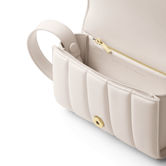 Mini Sadie Bag Crèmeのフラップを開いた内側には、ゴールドジッパー付きの内ポケットとマグネットボタンが配置されています。また、フラップの裏面にはDaniel Wellingtonのロゴが刻印されています。