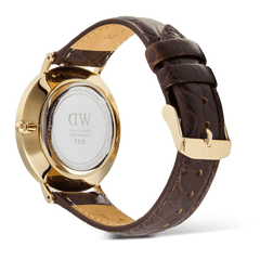Classic Roman Numerals Date Dark Brown Croc Belly Goldを裏蓋側から見たアングルです。ゴールドPVD加工のケースバックにはDaniel Wellingtonのロゴとシリアルナンバーが刻印されており、ダークブラウンのクロコダイルベリーレザーストラップはキャメルカラーの裏地とコントラストステッチで丁寧に仕上げられています。