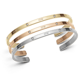 Daniel WellingtonのClassic Lumine Bracelet 3本セット（ゴールド、ローズゴールド、シルバー）。ポリッシュ仕上げのオープンカフデザインに、クリスタルとロゴが等間隔にあしらわれています。3色を重ねて身に着けることで、それぞれのトーンの違いが際立ち、華やかな印象を演出します。