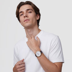 Classic Roman Numerals Date Dark Brown Croc Belly Goldを着用した男性モデルのスタイルです。白いTシャツにダークブラウンのクロコダイルベルトとゴールドケースが自然に調和し、カジュアルな装いにも上品なアクセントを加えています。