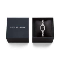 Quadro Mini Arch 3-link Onyx Sunray Silverが、ダークネイビーのブランドロゴ入りギフトボックスに収められた画像です。黒いクッションの上にシルバーのスクエア型腕時計が丁寧にセットされており、ギフトにふさわしいパッケージングをご覧いただけます。
