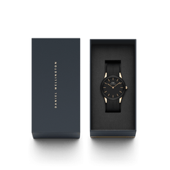 ダニエルウェリントンのギフトボックスに収められた「Iconic Motion Rose Gold」。ブラックダイヤルとラバーストラップの腕時計がクッション素材の上に丁寧にセットされ、箔押しのブランドロゴが施された蓋とともに撮影されています。