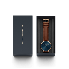 クラシック St Mawes Arctic Rose Goldが、ネイビーの専用ギフトボックスに収められた様子です。ブルーのサンレイダイヤルとブラウンのレザーストラップが黒いクッションの上に整えられ、贈り物にぴったりの上品なパッケージに仕上がっています。