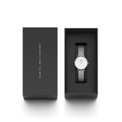 ダニエルウェリントンのブランドロゴがあしらわれたダークグレーのギフトボックスに収められたPetite Lumine Pressed Sterling。蓋を開けた状態で、クリスタルインデックスが輝くオフホワイトの文字盤とシルバーメッシュストラップが黒いクッションの上で美しく映えています。