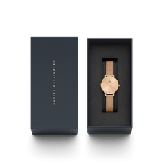 Daniel Wellington Petite Unitone ローズゴールドのギフトパッケージ画像。ネイビーカラーのブランドボックスに収められた、ローズゴールドのメッシュストラップ腕時計が、贈り物にふさわしい上品な佇まいを演出しています。