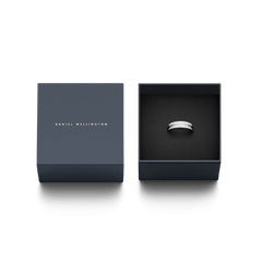 Daniel WellingtonのEmalie Ring Silverが、ネイビーのブランド専用ギフトボックスに収められています。箱の蓋にはブランドロゴが箔押しされ、ブラックのクッション上にリングが丁寧にセットされており、贈り物にぴったりの上品なパッケージです。