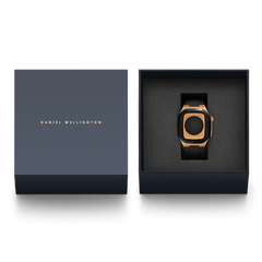 Daniel Wellington Switch Rose Goldのギフトボックス入り画像です。ネイビーの化粧箱の蓋には、ゴールドのブランドロゴが箔押しされています。箱を開けると、ブラックのクッション素材に収められたローズゴールドケースとブラックFKMラバーストラップが現れます。贈り物にもぴったりの上品なパッケージです。
