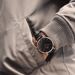 クラシックなYork Black Rose Goldを着用した男性の手元。グレーのニットとベージュのジャケットの袖口から、ブラック文字盤とローズゴールドケースがさりげなくのぞき、ダークブラウンのクロコ型押しレザーストラップが落ち着いた印象を添えています。
