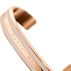 Emalie Bracelet Desert Sand Rose Goldを斜めから捉えたディテール画像です。ローズゴールドのフレームに挟まれたデザートサンドカラーのエナメルの質感や、内側に刻印されたDaniel Wellingtonのロゴが確認できます。