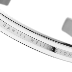 Emalie Braceletのシルバーのロゴ刻印部分を斜めから捉えたディテール画像です。ポリッシュ加工のステンレススチール表面に光が反射し、滑らかな質感とDaniel Wellingtonの繊細なレタリングが際立っています。