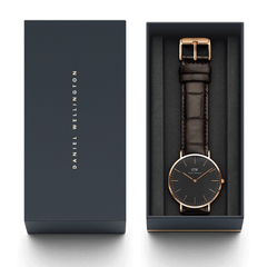 Classic York Black Rose Goldをネイビーの専用ギフトボックスに収めた画像です。ブラックの文字盤とダークブラウンのクロコ型押しレザーストラップが、ダークグレーのクッション素材の上に美しくレイアウトされ、贈り物にぴったりの上品なパッケージングとなっています。