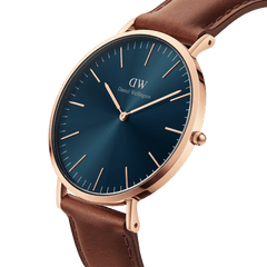 Classic St Mawes Arctic Rose Goldを斜めから捉えたクローズアップ画像。ブルーのサンレイダイヤルが光を受けて深みのある輝きを放ち、薄型のローズゴールドケースとブラウンレザーストラップのコントラストが際立つアングルです。