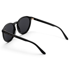 Arch Bio-Acetate Blackのサングラスを背面斜めから撮影した画像です。レンズ左側のフレーム内側にはゴールドのDaniel Wellingtonロゴが入り、ヒンジ部分にもゴールドのアクセントが施されています。