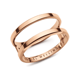 Daniel WellingtonのElan Dual Ring ローズゴールドモデル。2本のリングが平行に並ぶダブルリングデザインを採用し、ポリッシュ仕上げの表面が光を反射して美しく輝きます。下部のリングにはブランドロゴが刻印されています。