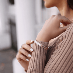 Emalie Bracelet Desert Sand Rose Goldを手首に着けたスタイリングイメージです。ベージュのリブニットの袖口からのぞくローズゴールドとデザートサンドカラーのブレスレットが、柔らかなトーンのコーディネートに自然になじんでいます。
