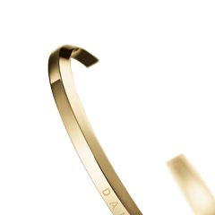 Daniel Wellington Classic Bracelet Goldのオープンカフ部分を斜めから捉えたアングルです。ポリッシュ仕上げのゴールドの曲線と、細身のカフの厚みや質感が際立つクローズアップ写真です。