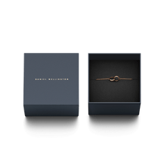 ダニエルウェリントンのElan Unity Bracelet ローズゴールドが、ネイビーの専用ギフトボックスに収められています。黒いクッションケースの上にケーブルチェーンとインターロッキングリングが美しく配置され、贈り物にぴったりの上品なパッケージです。
