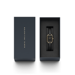 ダニエルウェリントンのブランドロゴを箔押ししたネイビーカラーのギフトボックスに収められたQuadro Pressed Sheffield Black Gold。ブラックレザーストラップとゴールドケースの腕時計が黒いクッションの上に上品に配置され、贈り物にぴったりのパッケージです。